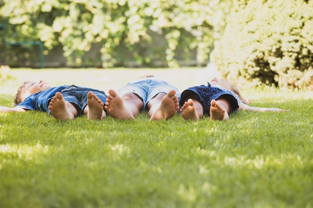 Groep kleine kinderen die blootsvoets op een groen gazon liggen Kindervoeten op de voorgrond