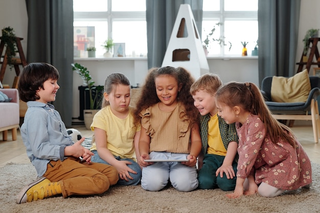 Groep kleine kinderen met digitale tablet die naar online tekenfilms kijkt