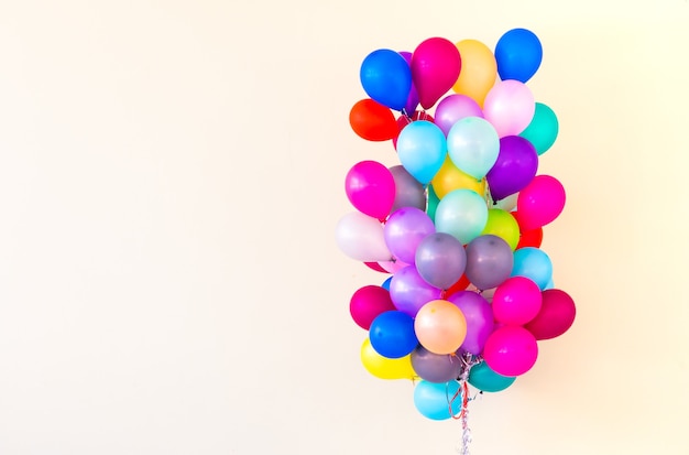 Groep kleurrijke ballonnen op pastelkleurige achtergrond.