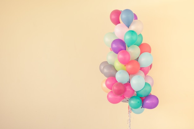 Groep kleurrijke ballonnen op pastelkleurige achtergrond.