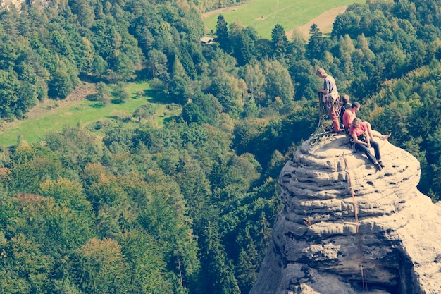 Groep klimmers op de top van de ronde rotsen op de bosachtergrond