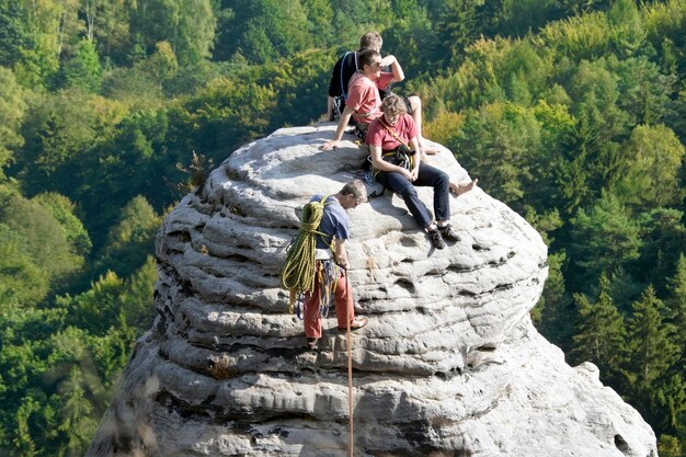 Groep klimmers op de top van de ronde rotsen op de bosachtergrond