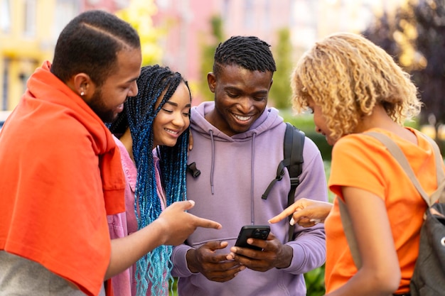 groep lachende Afro-Amerikaanse vrienden met mobiele telefoon die online op straat winkelt