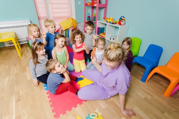 Groep lieve kinderen die op een vloer voor de leraar zitten en aandachtig luisteren Kleuters die leren tellen