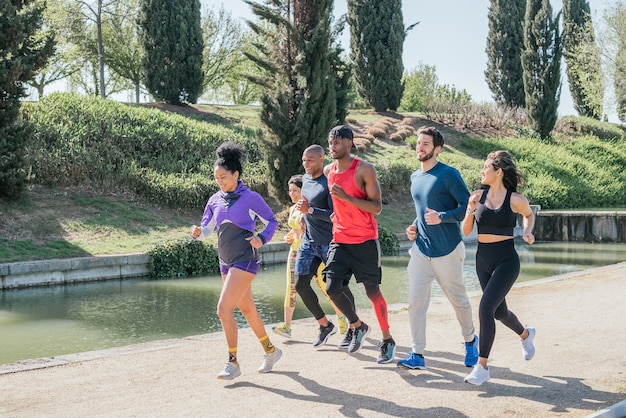 Groep lopers trainen in een park. Gelukkig en glimlachend.