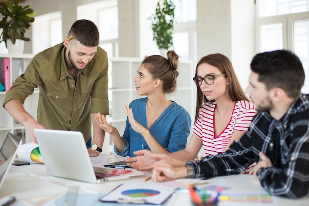 Groep mannen en vrouwen met een laptop die tijd doorbrengt op het werk Jonge creatieve mensen die samen een nieuw project bespreken in een modern kantoor