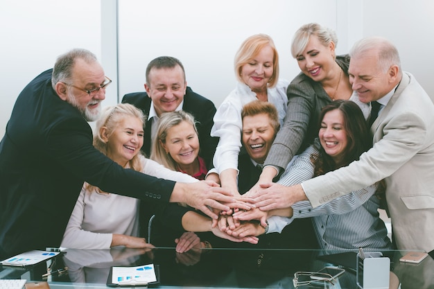 groep medewerkers die hun handpalmen over het bureau bundelen. het concept van teamwerk