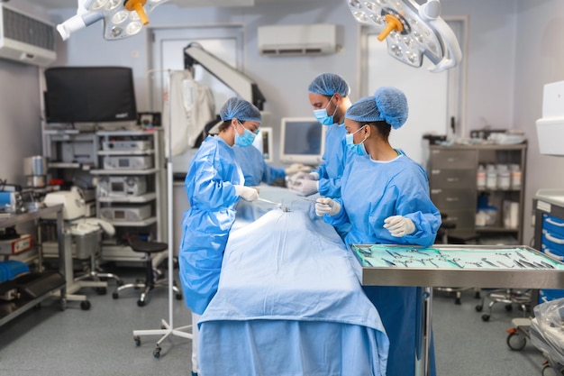 Groep medisch team die dringend een chirurgische ingreep uitvoert en de patiënt helpt in het theater in het ziekenhuis Medisch team dat een chirurgische ingreep uitvoert in een lichte moderne operatiekamer