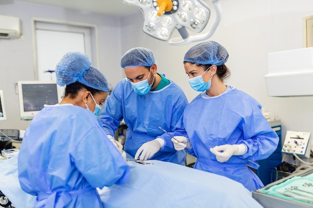 Groep medisch team die dringend een chirurgische ingreep uitvoert en de patiënt helpt in het theater in het ziekenhuis Medisch team dat een chirurgische ingreep uitvoert in een lichte moderne operatiekamer