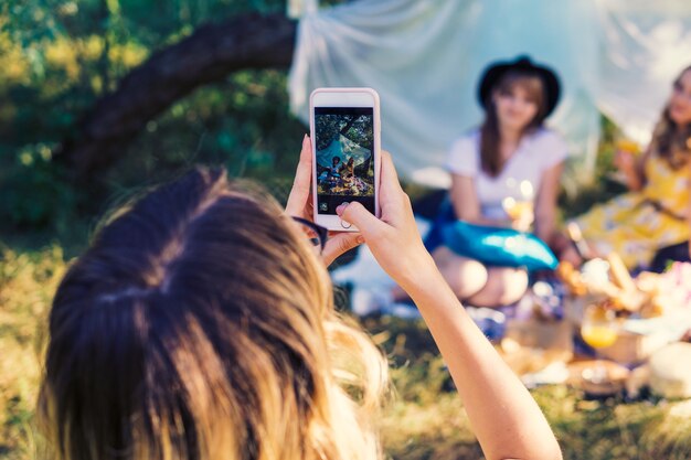 Groep meisjesvrienden die picknick buiten maken. Ze maken foto van smartphone