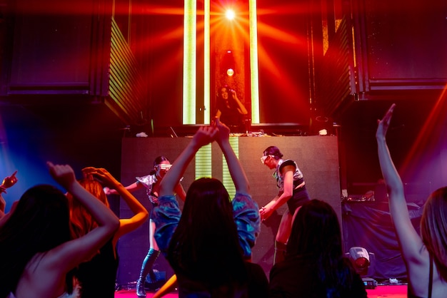 Groep mensen dansen in disco nachtclub op het ritme van muziek van dj op het podium