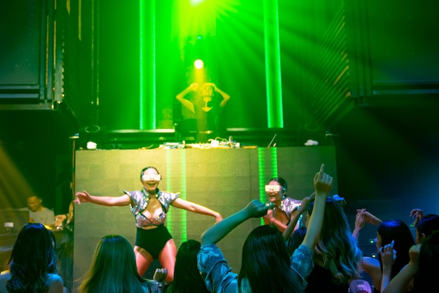 Groep mensen dansen in disco nachtclub op het ritme van muziek van dj op het podium