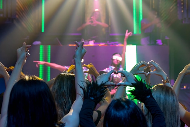 Groep mensen dansen in disco nachtclub op het ritme van muziek van DJ op het podium