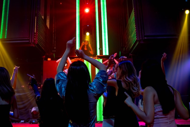 Foto groep mensen dansen in disco nachtclub op het ritme van muziek van dj op het podium