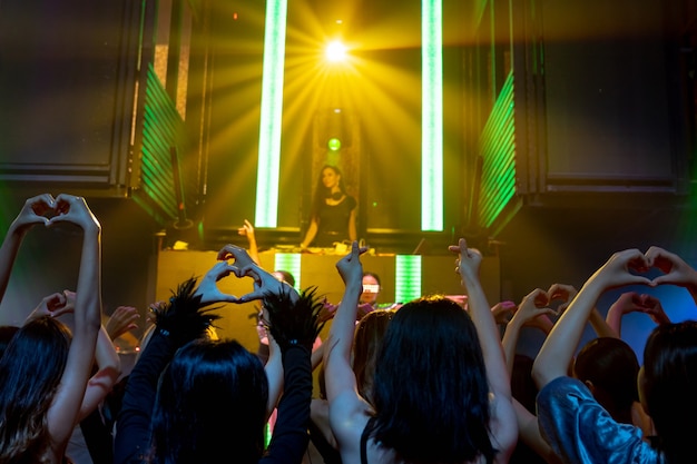Groep mensen dansen in disco nachtclub op het ritme van muziek van Dj op het podium