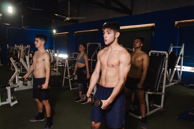 Groep mensen die lateraal vliegen met halters trainen in de sportschool.