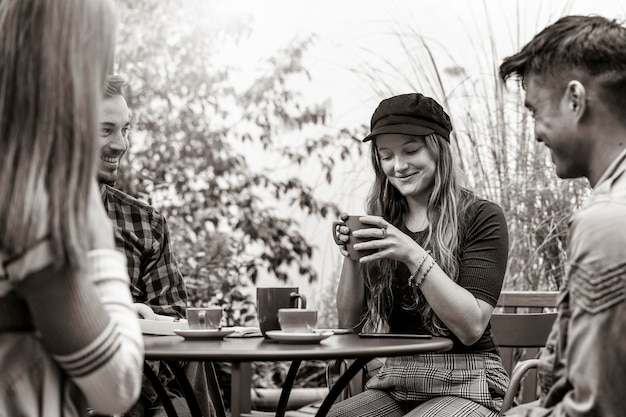 Groep mensen die latte drinken in de tuin van de koffiebar Vrienden praten en plezier hebben samen in hostel dehors Lifestyle concept met gelukkige jongens en meisjes in openluchtcafé Zwart-wit bewerking