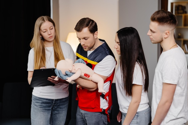 Groep mensen die leren hoe ze eerste hulp kunnen verlenen met dummy kind tijdens de training binnenshuis