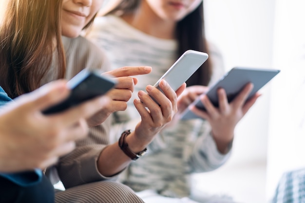 Groep mensen die mobiele telefoon en tablet-pc gebruiken en bekijken terwijl ze samen zitten