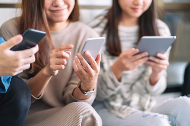 Groep mensen die mobiele telefoon en tablet-pc gebruiken en bekijken terwijl ze samen zitten