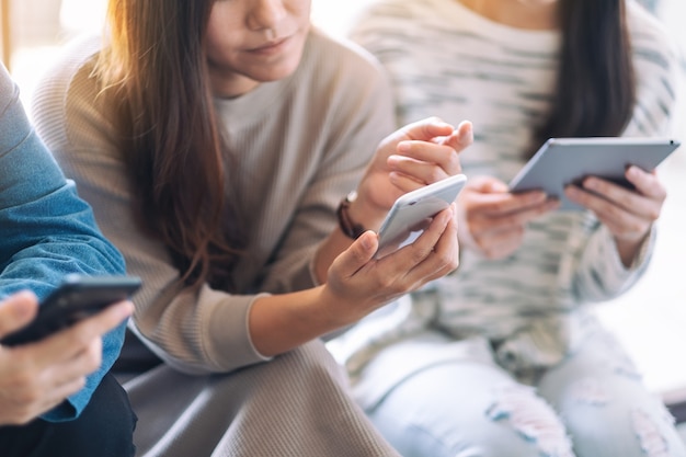 Groep mensen die mobiele telefoon en tablet-pc gebruiken en bekijken terwijl ze samen zitten