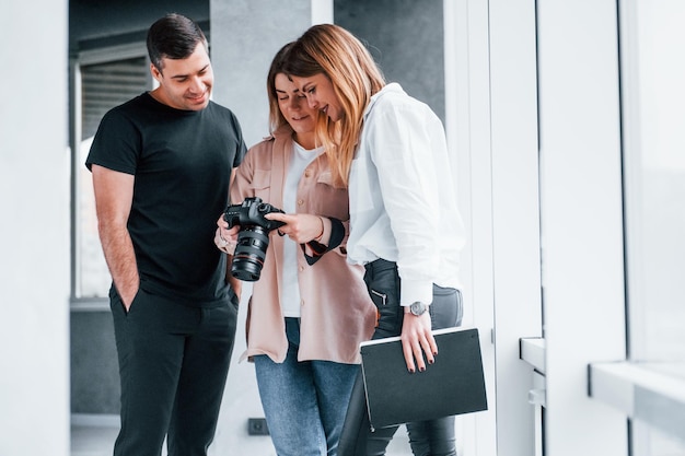 Groep mensen die samen binnen staan en naar foto's op de camera kijken