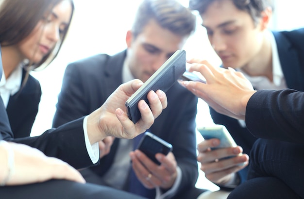 Groep mensen die smartphones gebruiken die tijdens de vergadering zitten.