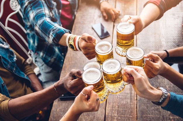 Groep mensen die van en een bier in brouwerijbar genieten roosteren - vriendschapsconcept met jongeren die pret hebben samen