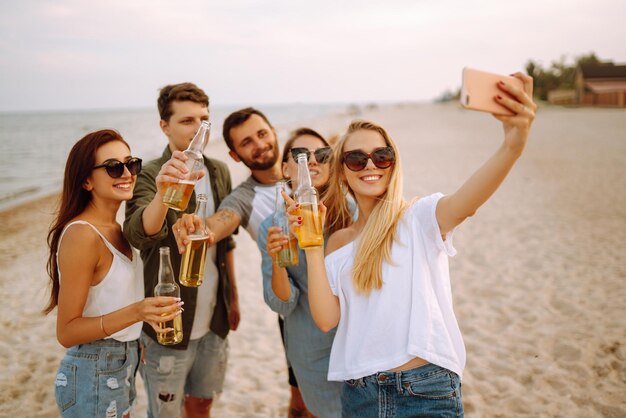 Groep mensen doen selfie met telefoon op het strand Jonge vrienden genieten samen van een zomerfeest