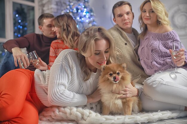 groep mensen en een hond in het nieuwjaarsinterieur / vrienden van jongens en meisjes Kerstavond met champagne