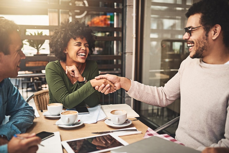Foto groep mensen handdrukken en koffie drinken als collega's voor het opbouwen van een zakelijk team of een bijeenkomst welkom positief en partnerschap in een restaurant voor het vieren van succes en samenwerking als webontwerper
