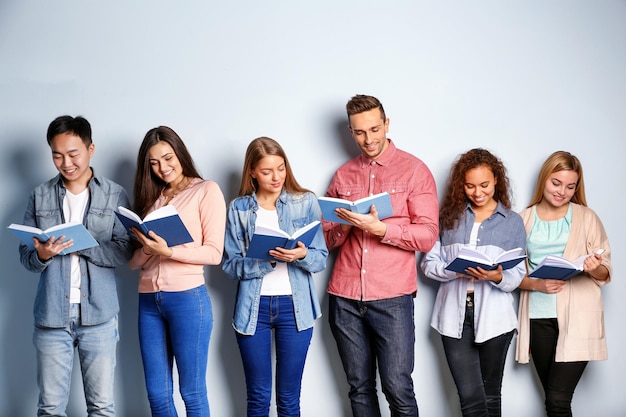 Groep mensen met boeken die zich dichtbij lichte muur bevinden