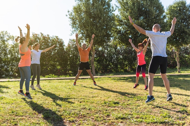 Groep mensen springen om op te warmen in een persoonlijke trainingssessie in het park.