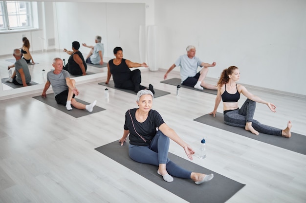 Groep mensen zittend op de vloer op matten en oefenen tijdens het beoefenen van yoga in de klas