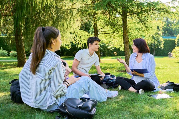 Groep middelbare scholieren met vrouwelijke leraar op campusgazon