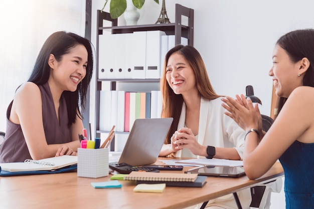 Groep mooie Aziatische vrouwen die in bureau aan besprekingszaken samenkomen.