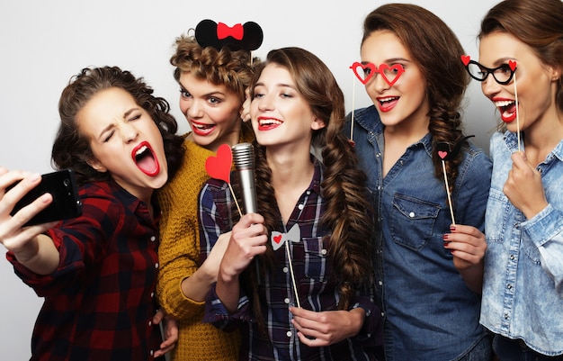 Groep mooie stijlvolle hipstermeisjes die karaoke zingen