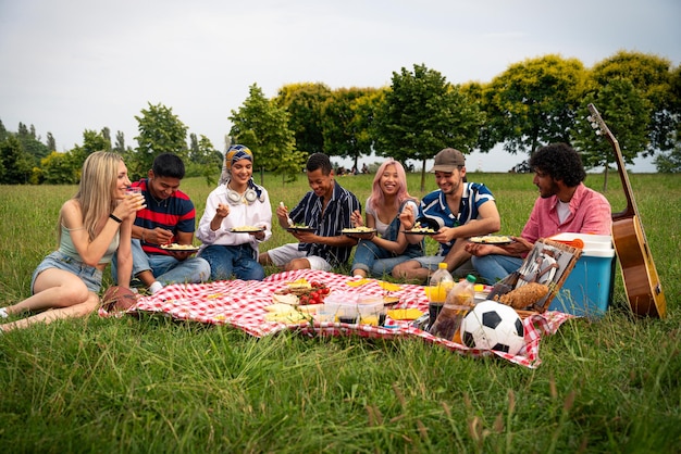 Groep multi-etnische tieners die tijd doorbrengen buiten op een picknick in het park