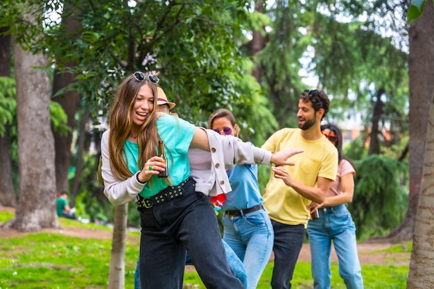 Groep multi-etnische vrienden op verjaardagsfeestje in het stadspark dansen zomerpret doen de conga