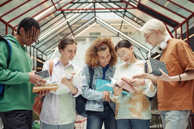 Foto groep multiculturele tienerjongens en -meisjes die collegeaantekeningen doornemen