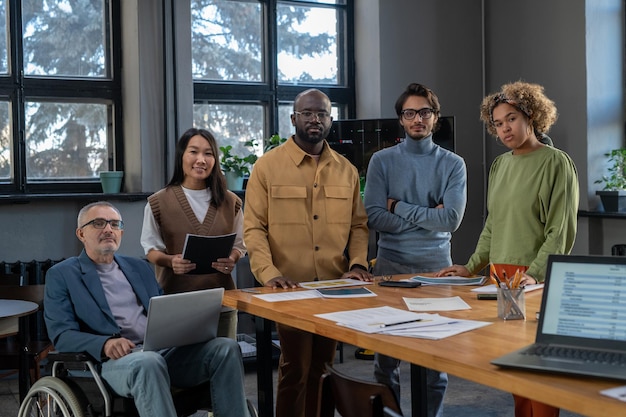 Groep multiraciale collega's die bij de tafel in de bestuurskamer staan