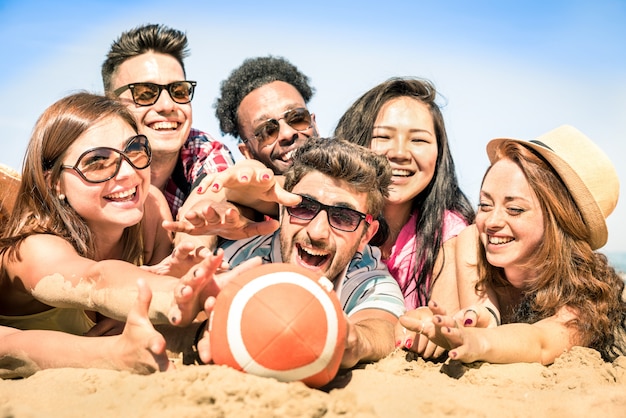 Groep multiraciale gelukkige vrienden die pret hebben bij strandspelen