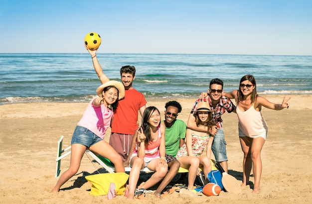 Groep multiraciale gelukkige vrienden die pret met de spelen van de strandsport hebben