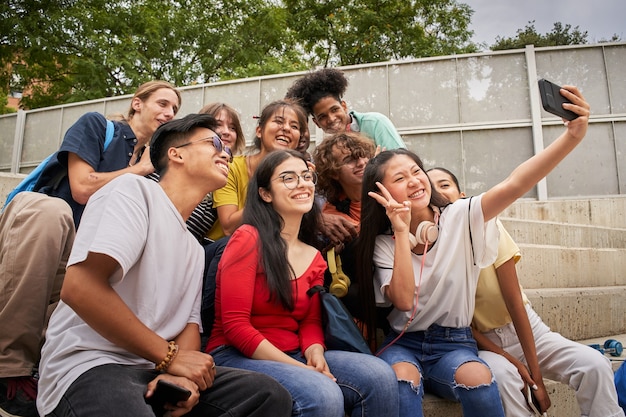 Groep multiraciale studenten die selfies nemen met het Chinese meisje van de mobiele telefoon toont haar vingers