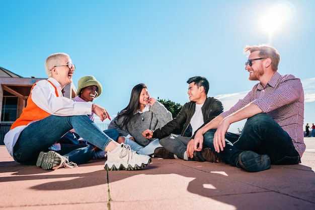 Groep multiraciale vrienden die op de vloer zitten lachen en plezier hebben