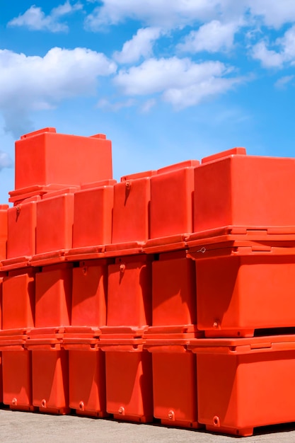 Groep oranje opvouwbare ijsemmers stapelen zich op de binnenplaats buiten de opslag tegen de blauwe lucht