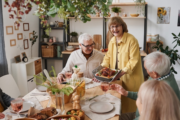 Groep oude vrienden die aan de eettafel zitten en samen eten tijdens de lunch thuis