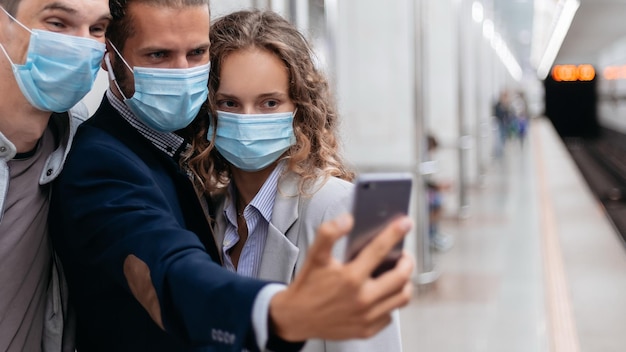 Groep passagiers met beschermende maskers die selfies nemen in de metro