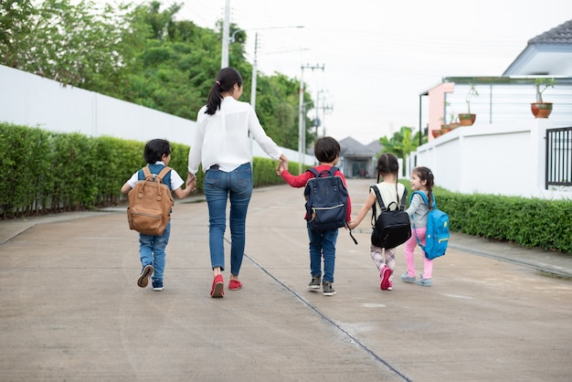 Groep peuterstudent en leraarsholdingshanden en het lopen aan huis.