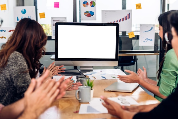 Groep professionele Aziatische zakelijke bijeenkomst en bespreking van strategie met nieuw opstartproject Creatieve zakenmensen plannen met desktopcomputer met witte mockup lege schermen in modern kantoor